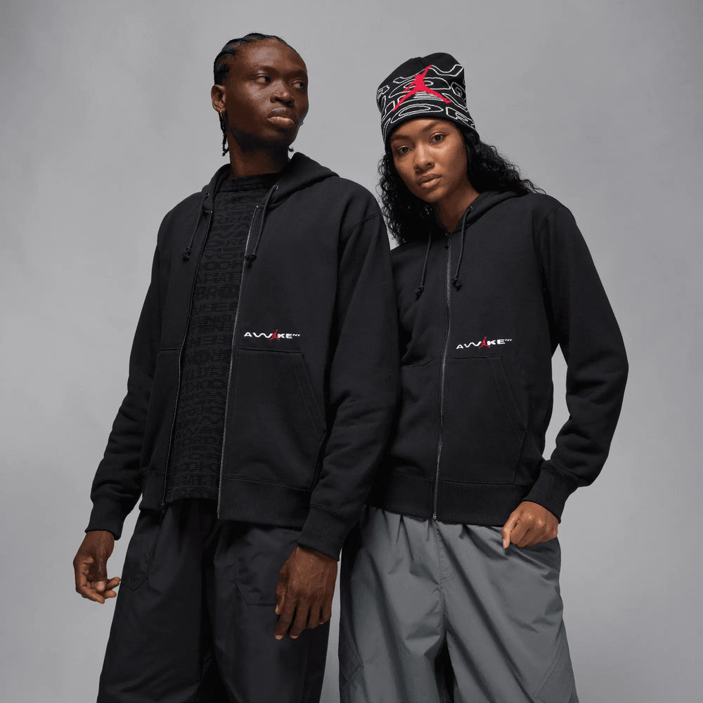 Two models wearing the black Jordan x Awake NY full-zip fleece hoodie with red logo details.